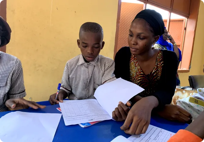 A facilitator helping a pupil with a worksheet